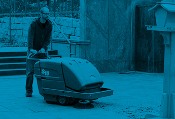 Arbeiter, der eine Kehrsaugmaschine von Tennant zur Reinigung der Außenanlagen verwendet